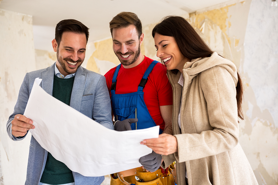 Homeowners consult with their home builder while looking over blueprints for the custom home