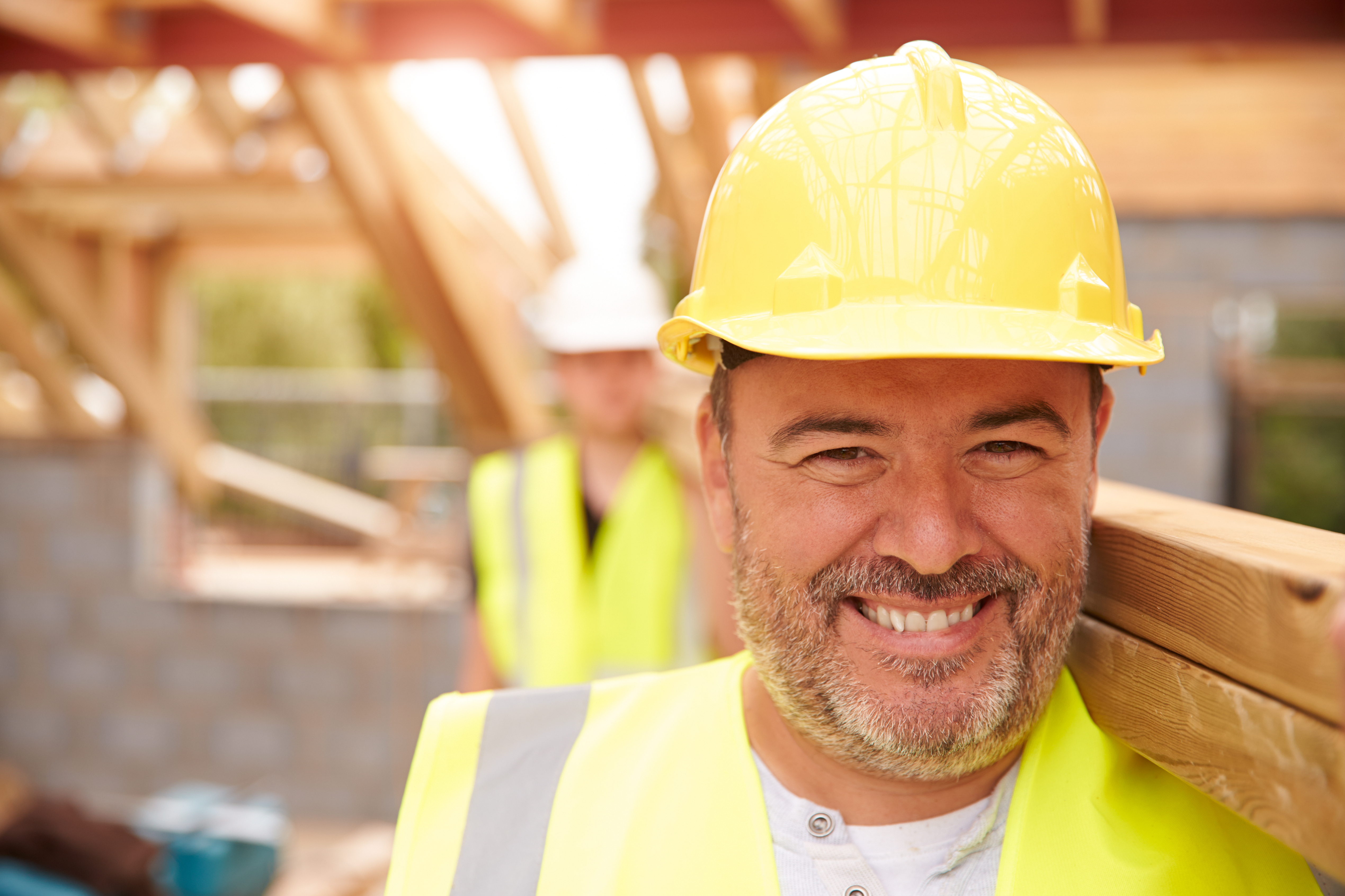 Custom home builders carrying wood planks on new home construction site