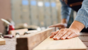 Carpenter placing hands on wood planks while working on a project