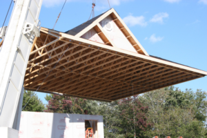 Home builders placing a prefabricated roof onto a modular home