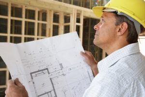 Custom home builder looking at floor plans on new home construction site